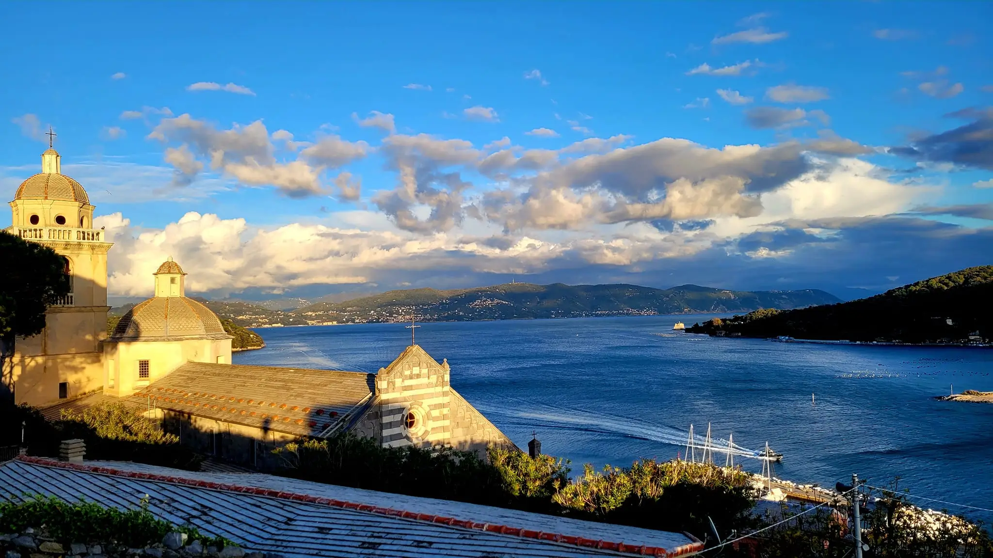 San Lorenzo Church on the top of the hill in Porto Venere overlooking blue sea mountains in the background
