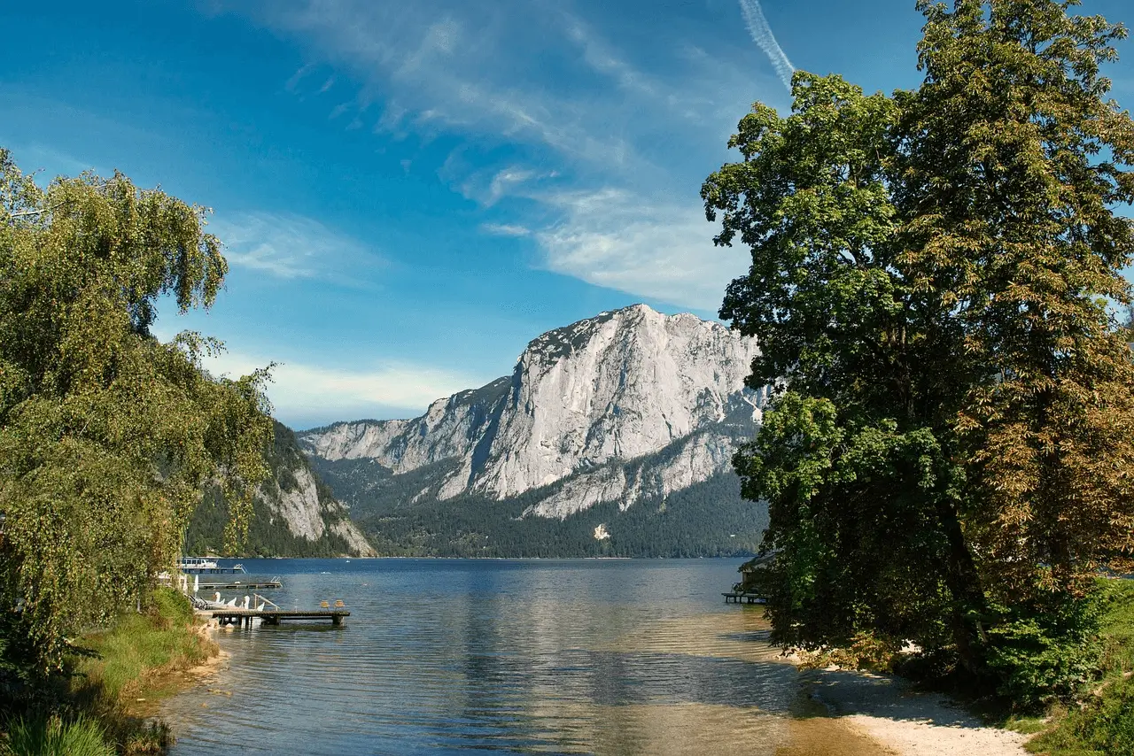 blue lake with white mountain peak in the bacground and turquoise lake framed by tall trees