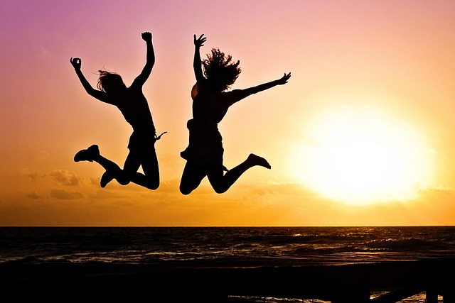 two happy people jumping in the air with a golden hour background