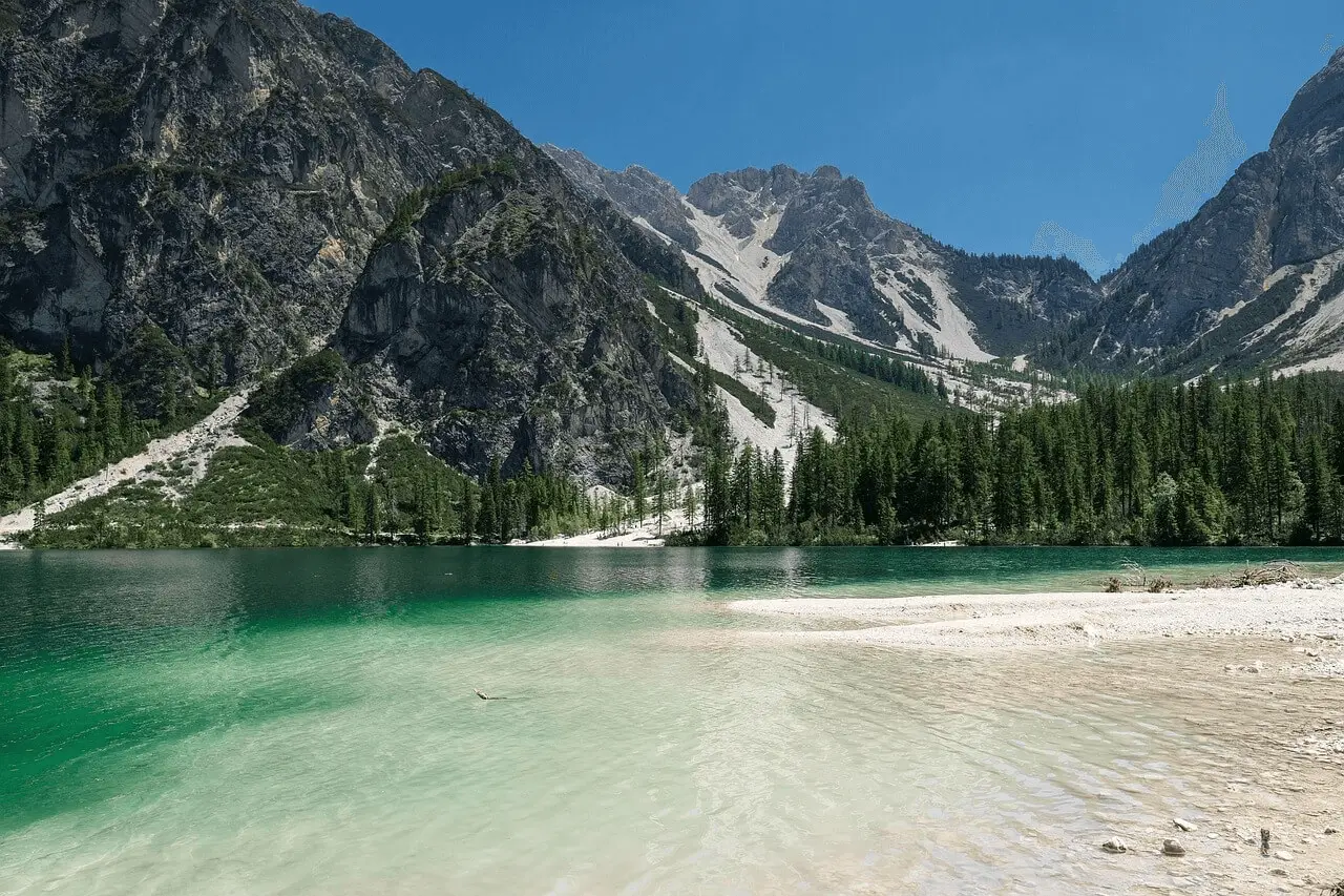 white sand and turquoise lake surrounded by mountains