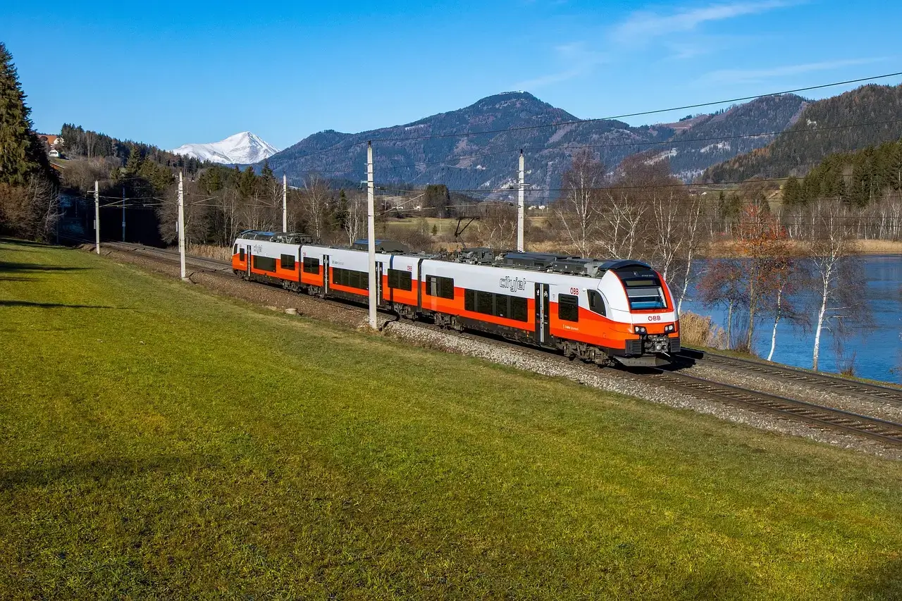 train is running in countryside with snowcaped mountains in the background