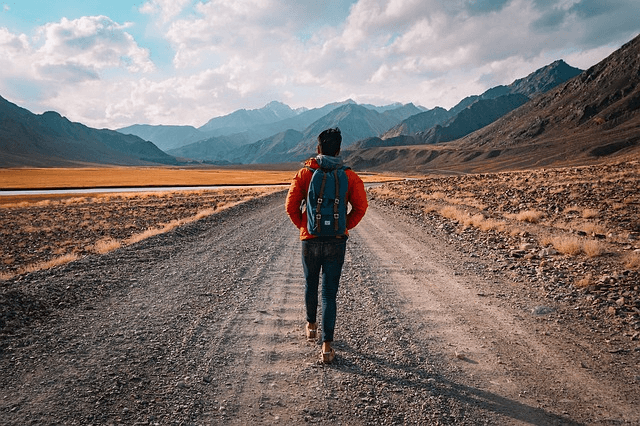 man is hiking on a trail in the mountains with a backpack with a scenic view in the background