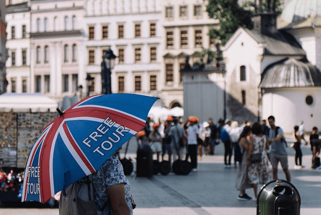 tour guide waiting for tourists with brand named umbrella for identification in historic city centre background