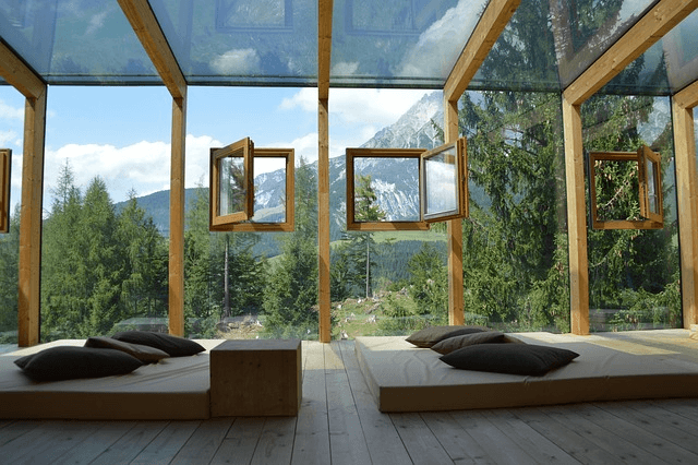 all glass transparent walls room with tow masive low beds with kushions and view to open forest